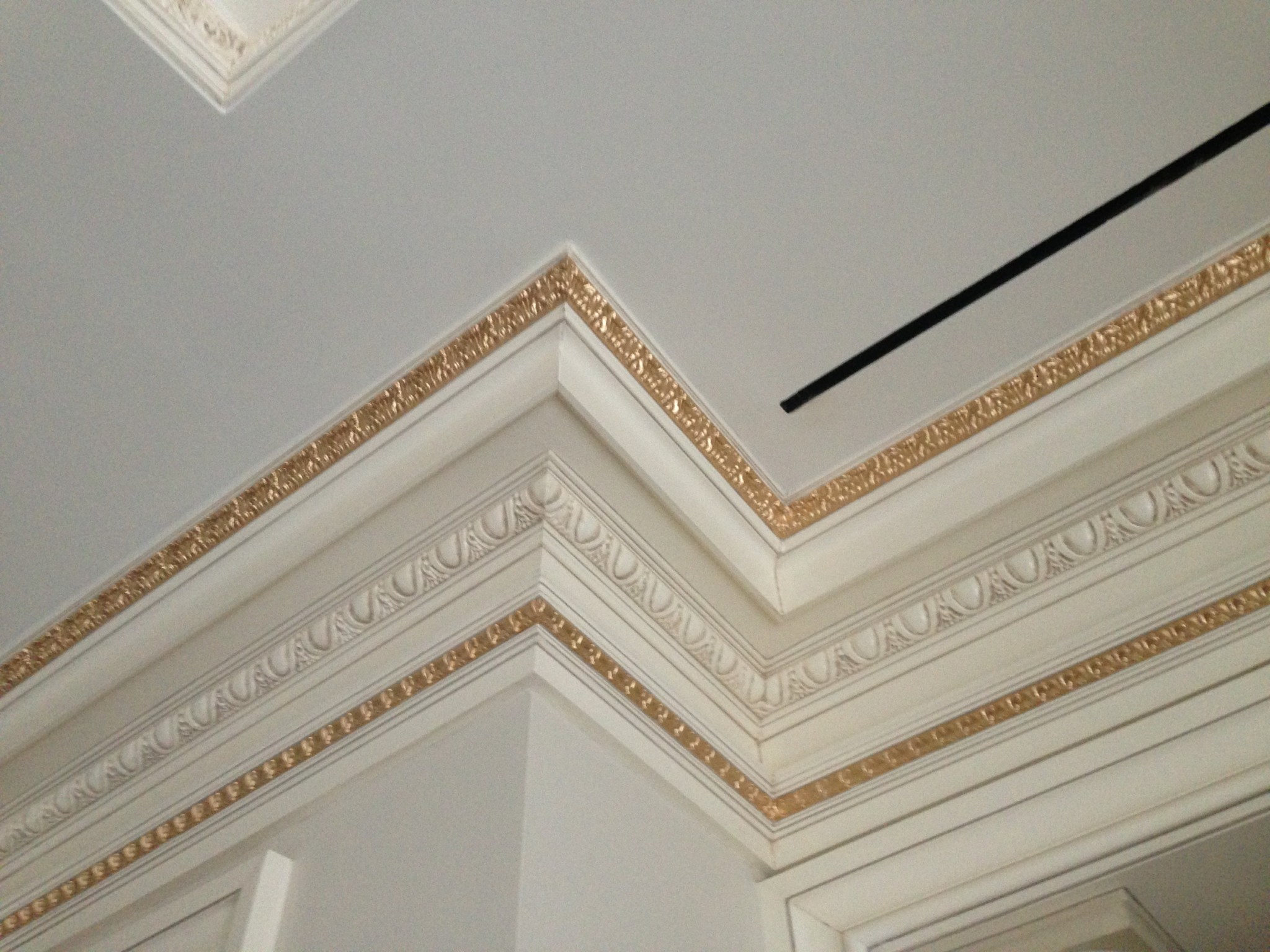 White ceiling and multi-layered crown moldings with gold painted details.